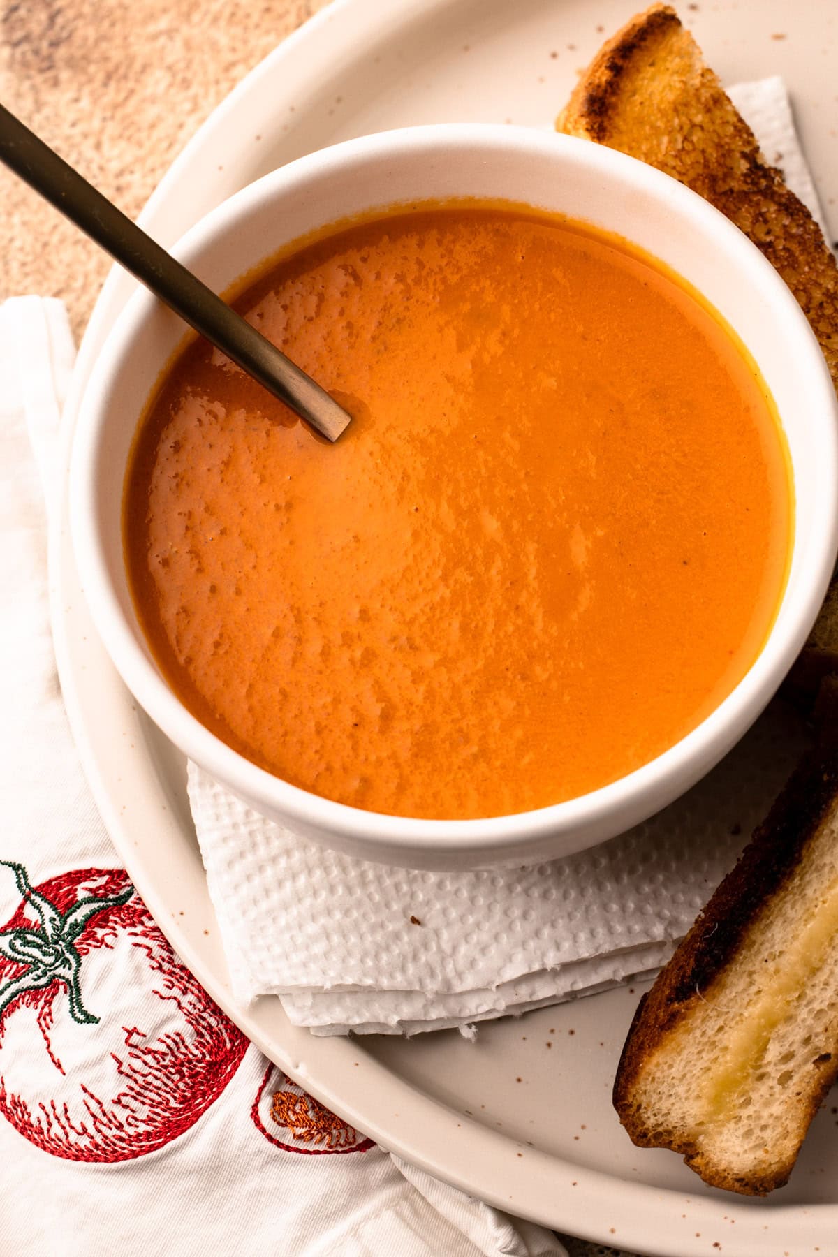 A bowl of tomato soup with a spoon resting in it.