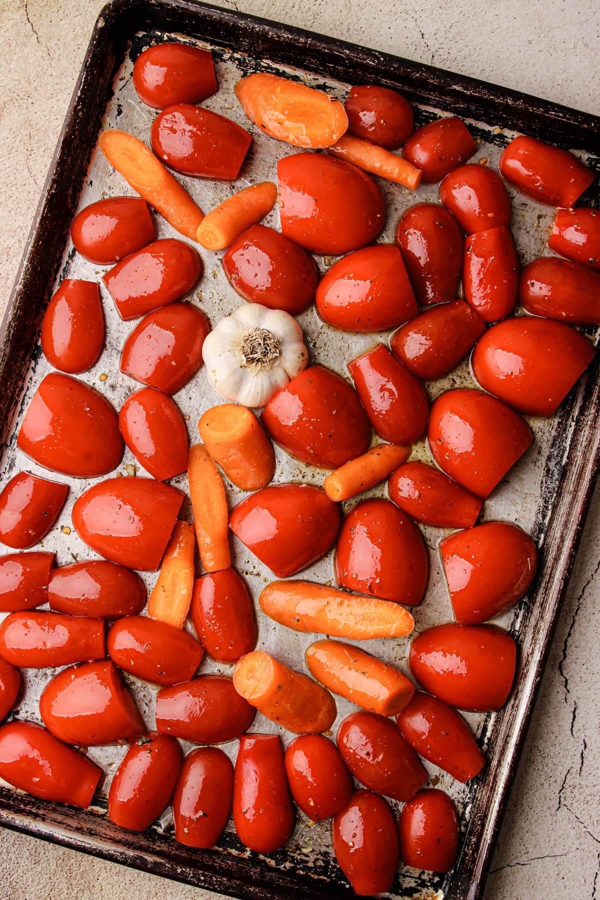 Tomatoes and garlic on a sheet pan before going into the oven.